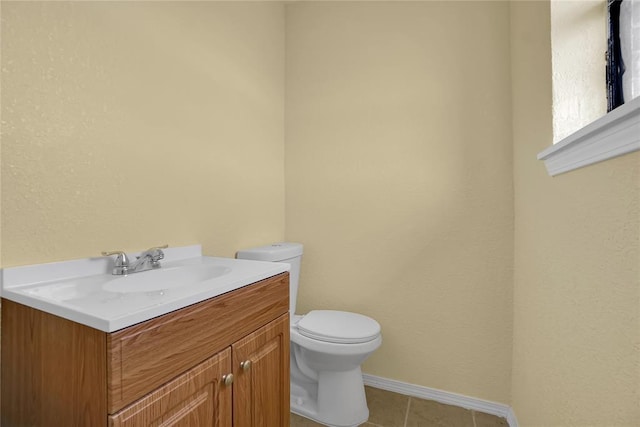 half bathroom featuring toilet, tile patterned floors, baseboards, and vanity