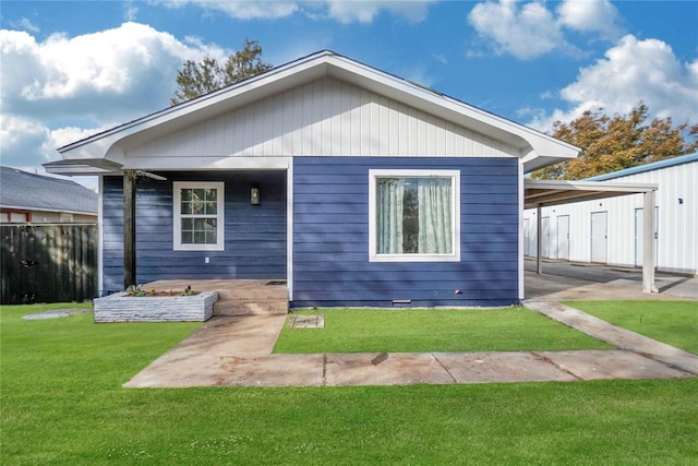 rear view of house featuring fence and a lawn