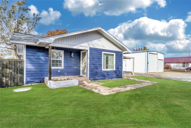 back of property featuring fence, a lawn, and an outdoor structure