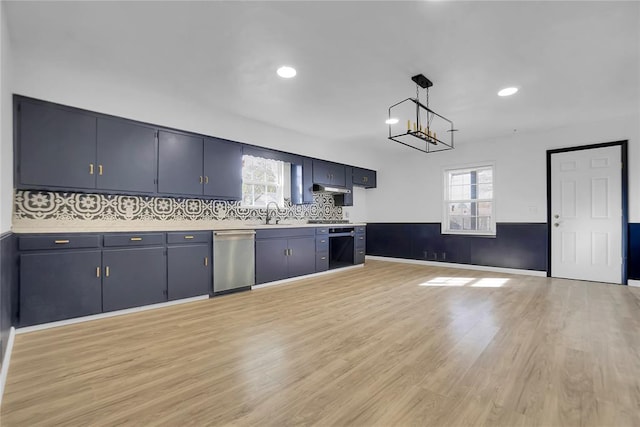 kitchen with under cabinet range hood, plenty of natural light, light wood finished floors, and stainless steel dishwasher