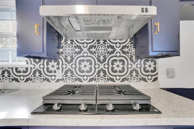 kitchen featuring decorative backsplash, stainless steel gas cooktop, blue cabinetry, and exhaust hood