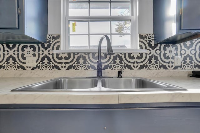 kitchen with light countertops, a sink, and backsplash