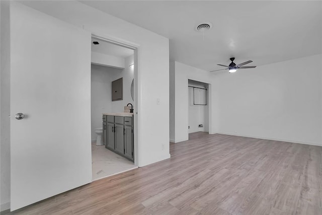 spare room featuring light wood-type flooring, a ceiling fan, visible vents, and a sink