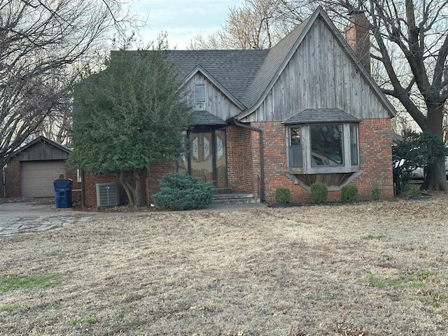 tudor house featuring brick siding, a chimney, and roof with shingles