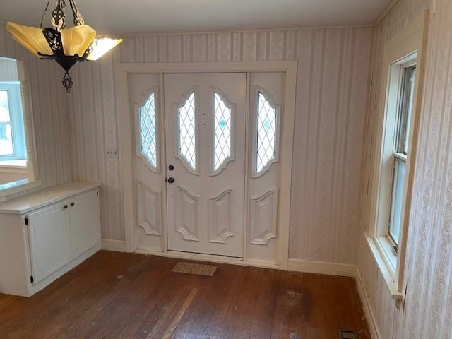 foyer entrance with wallpapered walls, baseboards, and dark wood-style flooring