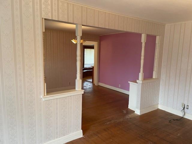 unfurnished room featuring wallpapered walls, baseboards, and dark wood-type flooring