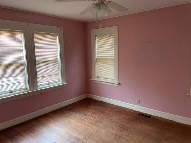 unfurnished room featuring baseboards, visible vents, and wood finished floors