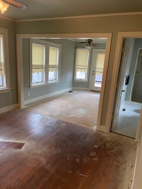 empty room featuring baseboards, wood finished floors, a ceiling fan, and crown molding