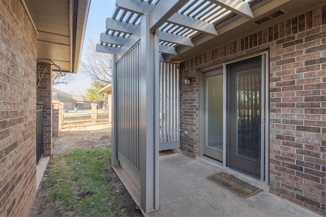 entrance to property with brick siding, a pergola, and fence