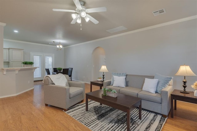 living room featuring visible vents, arched walkways, baseboards, and light wood-style flooring