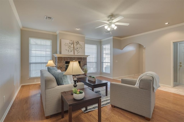 living room with visible vents, arched walkways, plenty of natural light, and a fireplace