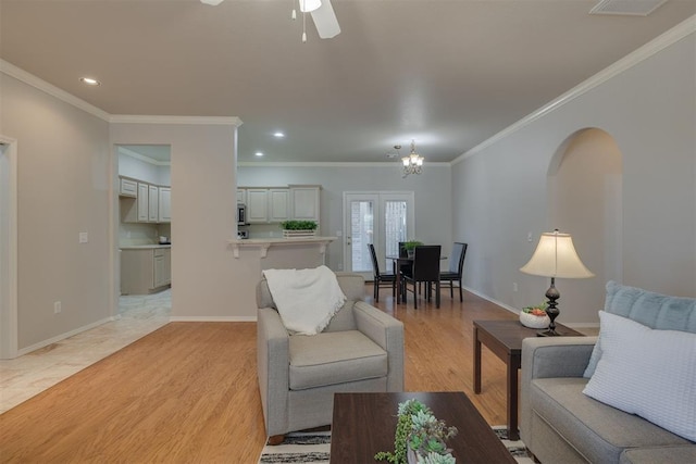 living area featuring baseboards, recessed lighting, arched walkways, ceiling fan with notable chandelier, and light wood-type flooring