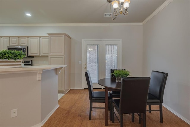 dining area featuring crown molding, light wood-style floors, visible vents, and baseboards