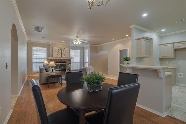 dining area with visible vents, a brick fireplace, and light wood-type flooring