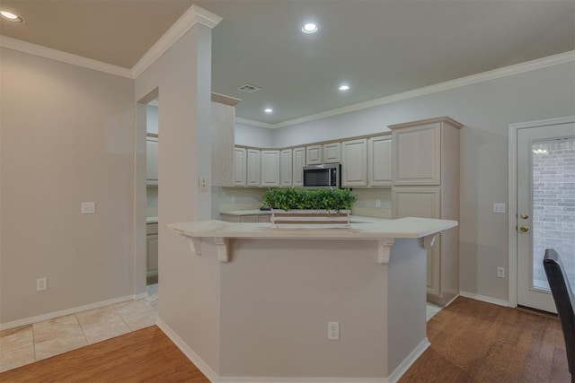 kitchen featuring stainless steel microwave, visible vents, light wood-style flooring, and light countertops