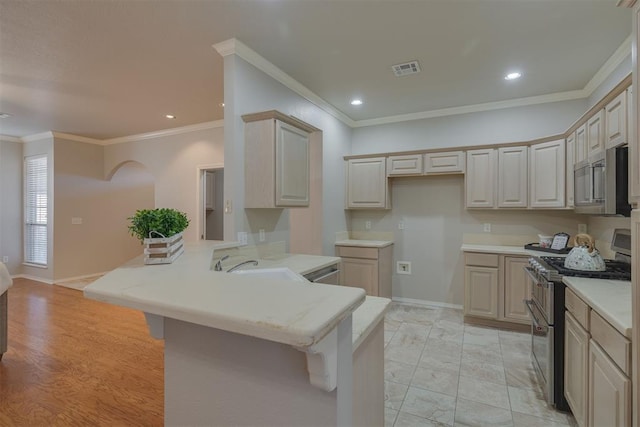 kitchen with appliances with stainless steel finishes, a breakfast bar, a peninsula, and a sink