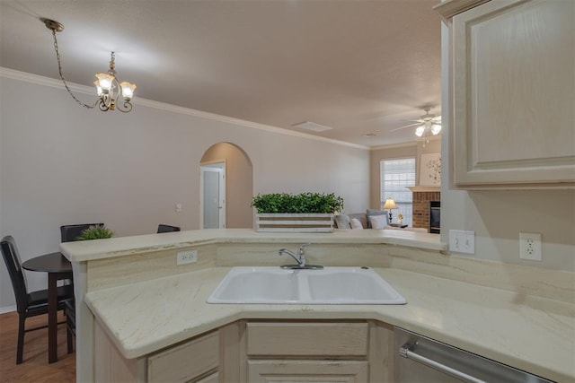 kitchen with a brick fireplace, open floor plan, ornamental molding, stainless steel dishwasher, and a sink