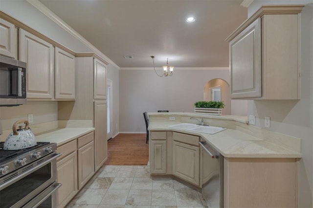 kitchen featuring a sink, appliances with stainless steel finishes, a peninsula, crown molding, and a chandelier