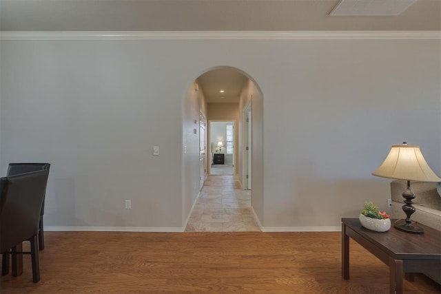 hallway with visible vents, arched walkways, baseboards, and crown molding