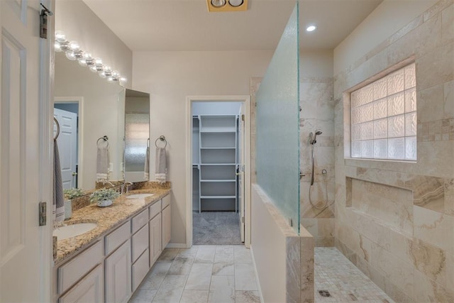 full bathroom featuring a walk in closet, double vanity, walk in shower, and a sink