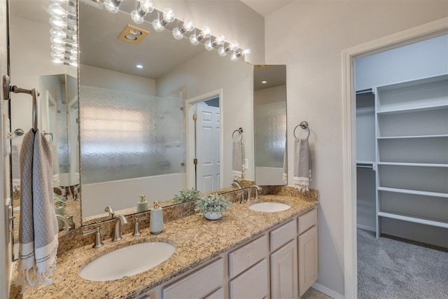 bathroom with a sink, a walk in closet, walk in shower, and double vanity