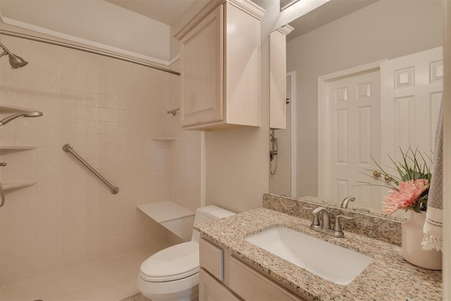 bathroom with vanity, toilet, and a tile shower