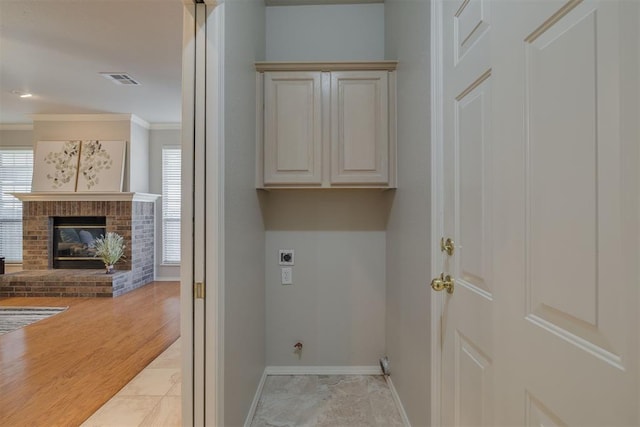 washroom featuring baseboards, hookup for an electric dryer, a fireplace, cabinet space, and ornamental molding