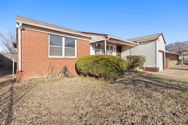 view of front facade featuring a garage, brick siding, fence, and driveway