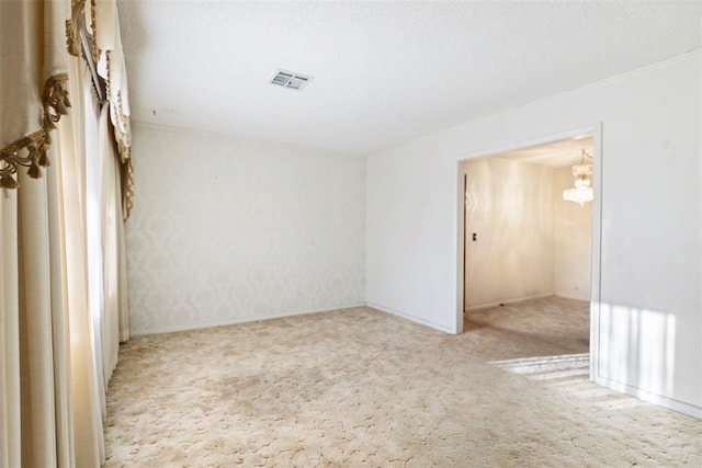 spare room with carpet, visible vents, and a textured ceiling