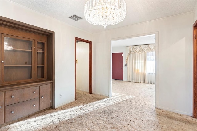 interior space with baseboards, visible vents, light colored carpet, a textured ceiling, and a notable chandelier