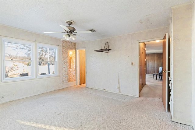 unfurnished room featuring a textured ceiling, carpet floors, ceiling fan, and visible vents