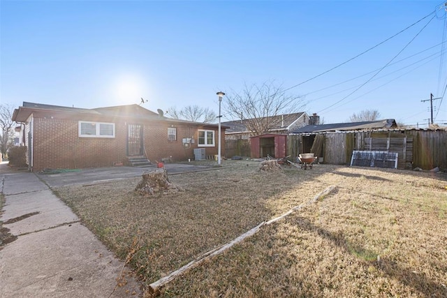 back of house with an outbuilding, a storage shed, brick siding, fence, and a yard