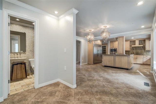 kitchen featuring built in appliances, a chandelier, light brown cabinets, backsplash, and wall chimney exhaust hood