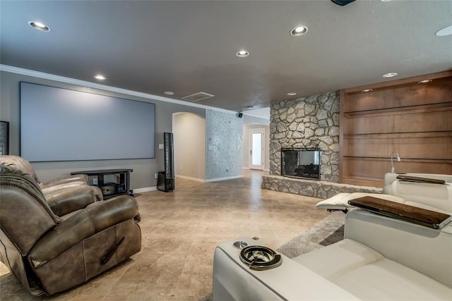 cinema room featuring visible vents, arched walkways, baseboards, ornamental molding, and a fireplace