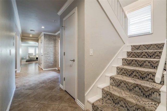 stairs featuring arched walkways, baseboards, ornamental molding, tile patterned flooring, and recessed lighting