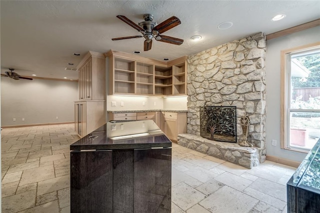 kitchen with a fireplace, a kitchen island, baseboards, open shelves, and stone tile flooring