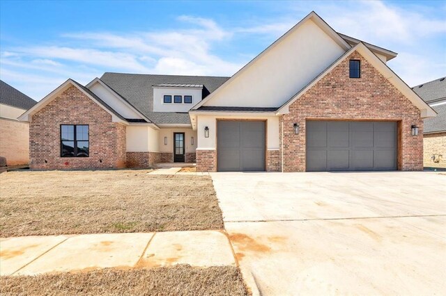 view of front of home with brick siding, stucco siding, an attached garage, a front yard, and driveway