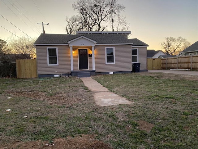 bungalow-style home featuring roof with shingles, fence, a patio, and a front yard