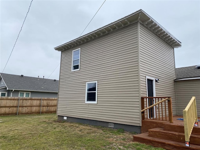 rear view of property featuring a yard, crawl space, and fence