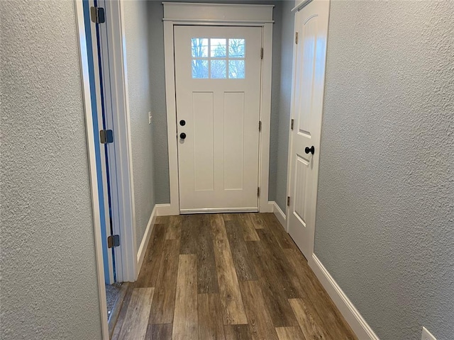 entryway with dark wood-style floors, a textured wall, and baseboards