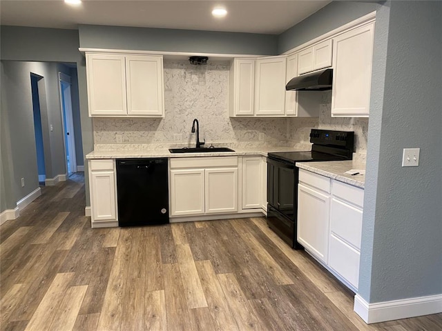 kitchen with backsplash, a sink, wood finished floors, under cabinet range hood, and black appliances