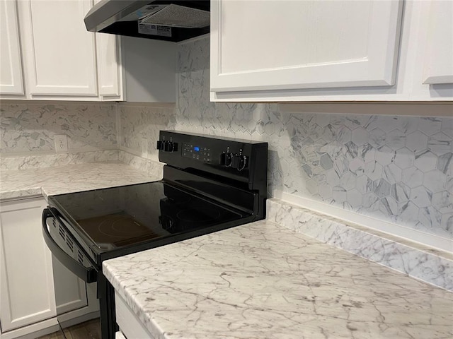 kitchen featuring under cabinet range hood, electric range, white cabinets, decorative backsplash, and light stone countertops