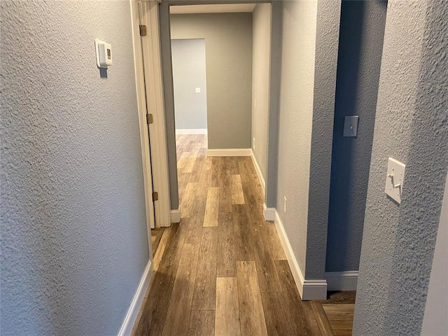 hallway with baseboards, dark wood finished floors, and a textured wall