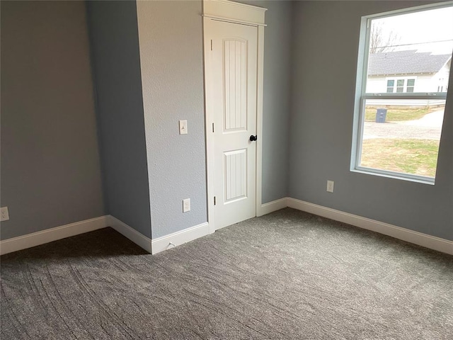 carpeted spare room featuring baseboards