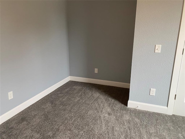 unfurnished room featuring baseboards and dark colored carpet