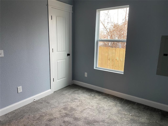 carpeted empty room with electric panel and baseboards