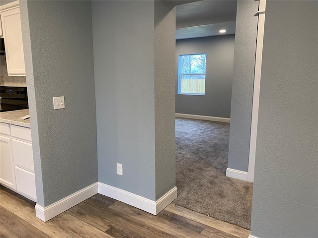 corridor featuring dark wood-style floors, baseboards, and a textured wall