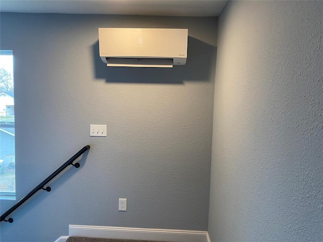 stairs with an AC wall unit and a textured wall