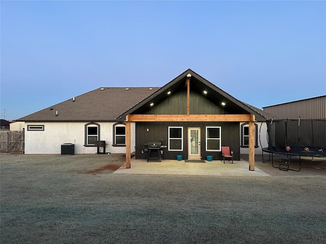 rear view of house with a trampoline, fence, central AC, and a patio