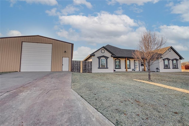 view of front of home with an outbuilding, concrete driveway, a front yard, fence, and a garage